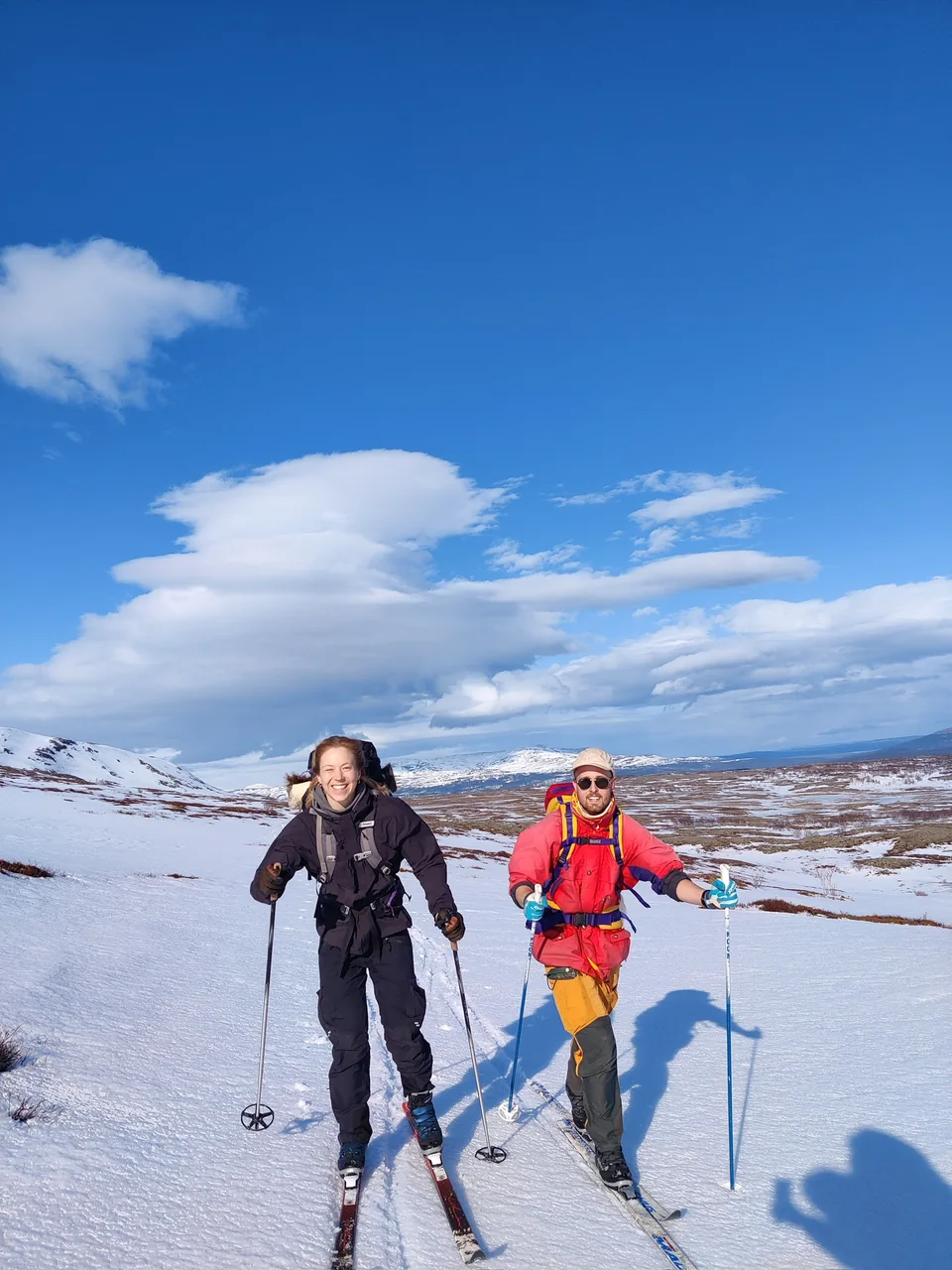 Två glada skidåkare i ett snötäckt fjällandskap.