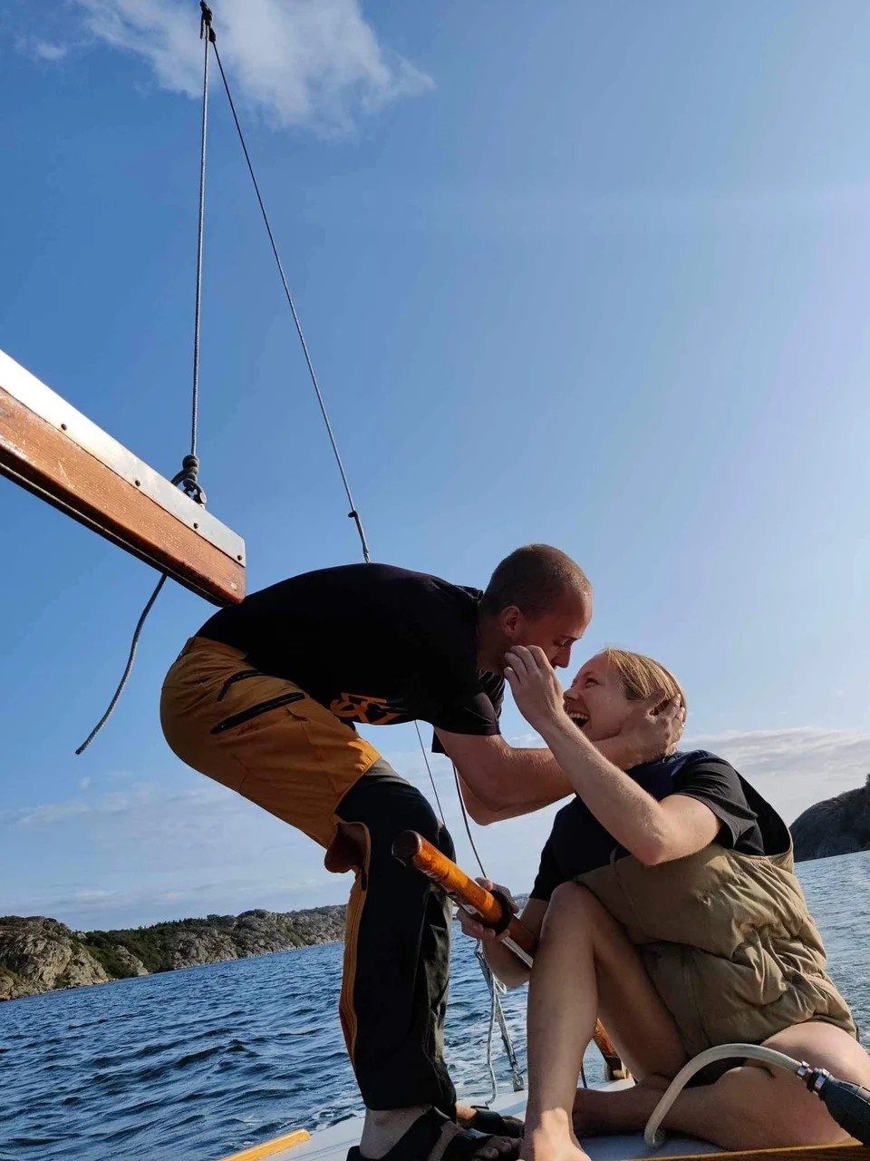 Ett skratt och en kram ombord på en segelbåt i solen.
